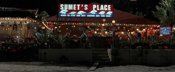 Movie still from “The Beach” (2000), directed by Danny Boyle – People are standing outside of a restaurant at night; Extreme Wide shot, High angle