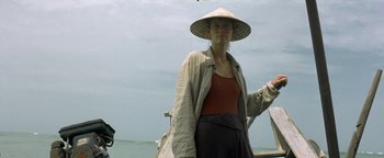 Movie still from “The Beach” (2000), directed by Danny Boyle – A woman wearing a hat standing next to a body of water; Medium shot, Low angle