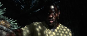 Movie still from “The Beach” (2000), directed by Danny Boyle – A man with a yellow shirt is looking at the camera; Close Up shot, Low angle