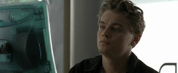 Movie still from “The Beach” (2000), directed by Danny Boyle – A person sitting down with his eyes wide open; Close Up shot, Over the shoulder angle