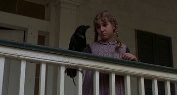 Movie still from “The Beguiled” (1971), directed by Don Siegel – A young girl holding a black bird on a porch; Close Up shot, Low angle