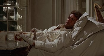 Movie still from “The Beguiled” (1971), directed by Don Siegel – A man laying in a bed in a room; Medium shot, Low angle