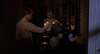 Movie still from “The Beguiled” (1971), directed by Don Siegel – Two women are lighting candles in front of a mirror; Medium shot, Over the shoulder angle