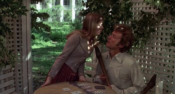 Movie still from “The Beguiled” (1971), directed by Don Siegel – A man and a woman playing a card game outside; Medium shot, Over the shoulder angle