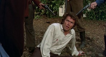 Movie still from “The Beguiled” (1971), directed by Don Siegel – A man in a white shirt is sitting on the ground; Medium shot, Over the shoulder angle