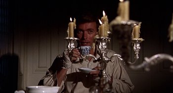 Movie still from “The Beguiled” (1971), directed by Don Siegel – A man holding a coffee cup in front of candles; Medium shot, Low angle