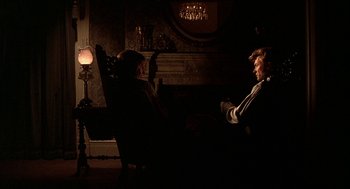 Movie still from “The Beguiled” (1971), directed by Don Siegel – Two people sitting in a living room in the dark; Wide shot, Over the shoulder angle