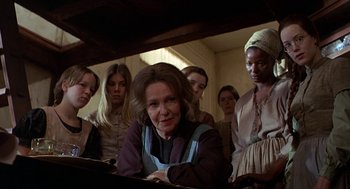 Movie still from “The Beguiled” (1971), directed by Don Siegel – A group of people standing around a woman in front of a laptop; Medium shot, Low angle