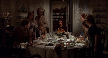 Movie still from “The Beguiled” (1971), directed by Don Siegel – A group of people sitting around a table with food on it; Wide shot, High angle