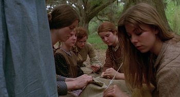 Movie still from “The Beguiled” (1971), directed by Don Siegel – A group of young women sitting in a forest; Medium shot, Low angle
