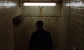 Movie still from “The Believer” (2001), directed by Henry Bean – A man standing in a tiled bathroom looking at the light; Medium shot, High angle