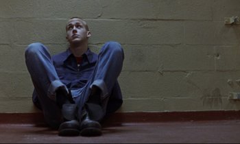 Movie still from “The Believer” (2001), directed by Henry Bean – A man sitting on the ground with his legs crossed; Wide shot, High angle
