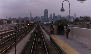 Movie still from “The Believer” (2001), directed by Henry Bean – A view of a train station with a view of the city; Extreme Wide shot, High angle