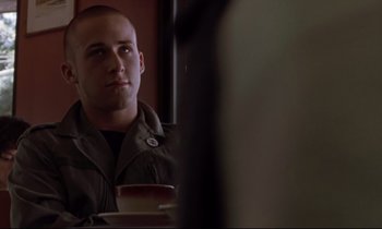 Movie still from “The Believer” (2001), directed by Henry Bean – A man sitting at a table with a cup of coffee in front of him; Close Up shot, Over the shoulder angle