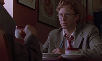 Movie still from “The Believer” (2001), directed by Henry Bean – A man sitting at a table with a cup of coffee; Close Up shot, Over the shoulder angle