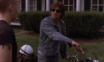 Movie still from “The Believer” (2001), directed by Henry Bean – A man riding a bike in a field with a helmet on; Medium shot, Low angle