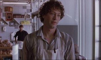 Movie still from “The Believer” (2001), directed by Henry Bean – A man with curly brown hair wearing an apron; Close Up shot, Over the shoulder angle