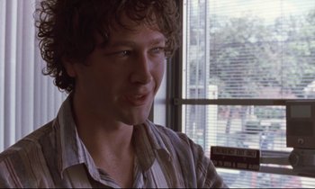 Movie still from “The Believer” (2001), directed by Henry Bean – A man with curly brown hair wearing a striped shirt; Close Up shot, Over the shoulder angle