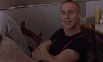 Movie still from “The Believer” (2001), directed by Henry Bean – A man sitting at a table with his arms crossed; Medium shot, High angle