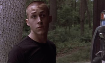 Movie still from “The Believer” (2001), directed by Henry Bean – A man in a black shirt is in the woods; Close Up shot, Over the shoulder angle