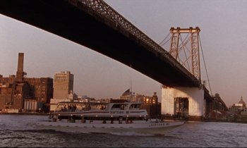 Movie still from “The Believer” (2001), directed by Henry Bean – A boat on a river under a bridge; Extreme Wide shot, Low angle