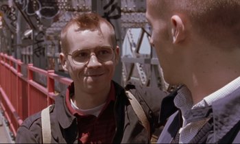 Movie still from “The Believer” (2001), directed by Henry Bean – A man in a jacket and glasses talking to another man; Close Up shot, Over the shoulder angle