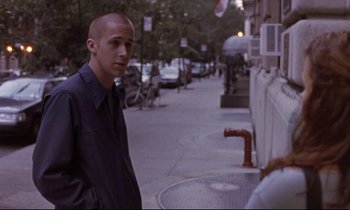 Movie still from “The Believer” (2001), directed by Henry Bean – A young man standing on a sidewalk next to a fire hydrant; Medium shot, Over the shoulder angle