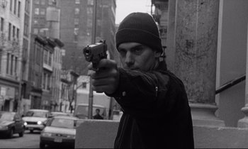 Movie still from “The Believer” (2001), directed by Henry Bean – A man holding a gun in his right hand while standing on the street; Close Up shot, Low angle