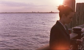 Movie still from “The Believer” (2001), directed by Henry Bean – A woman sitting on a pier looking out at the water; Medium shot, Over the shoulder angle