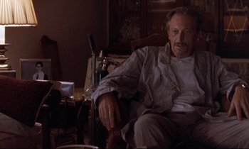 Movie still from “The Believer” (2001), directed by Henry Bean – An older man sitting on a chair in a living room; Medium shot, Low angle