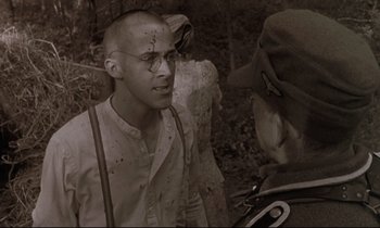 Movie still from “The Believer” (2001), directed by Henry Bean – A man in a hat and glasses talking to another man in a hat; Close Up shot, Over the shoulder angle