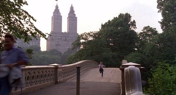 Movie still from “The Believers” (1987), directed by John Schlesinger – A person running across a bridge in front of a large building; Extreme Wide shot, High angle