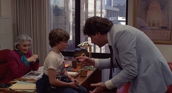 Movie still from “The Believers” (1987), directed by John Schlesinger – A young boy sitting in front of an older man; Medium shot, Over the shoulder angle