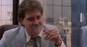Movie still from “The Believers” (1987), directed by John Schlesinger – A person wearing a suit smoking a cigarette; Close Up shot, Low angle
