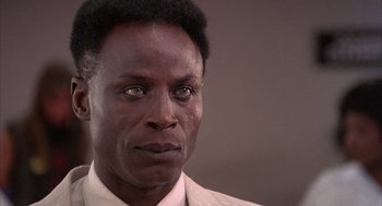 Movie still from “The Believers” (1987), directed by John Schlesinger – A person wearing a suit and tie; Close Up shot, Low angle
