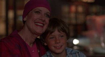 Movie still from “The Believers” (1987), directed by John Schlesinger – An older woman and a young boy smiling for the camera; Close Up shot, Over the shoulder angle