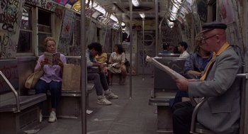 Movie still from “The Believers” (1987), directed by John Schlesinger – People are sitting in a subway car while reading newspapers; Wide shot, High angle