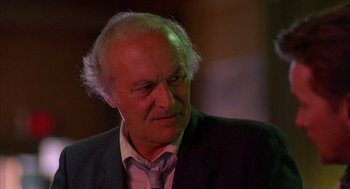 Movie still from “The Believers” (1987), directed by John Schlesinger – An older man in a suit and tie looking to his left; Close Up shot, Low angle