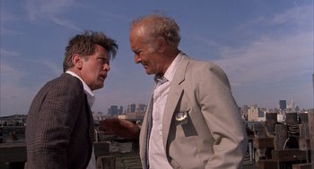 Movie still from “The Believers” (1987), directed by John Schlesinger – Two older men are talking on the roof of a building; Medium shot, Low angle