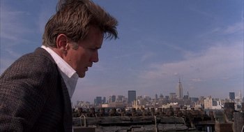 Movie still from “The Believers” (1987), directed by John Schlesinger – A person looking at a city skyline; Medium shot, Low angle