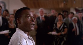 Movie still from “The Believers” (1987), directed by John Schlesinger – A man standing in front of a group of people; Close Up shot, Low angle