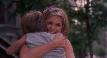 Movie still from “The Believers” (1987), directed by John Schlesinger – A woman is hugging a young boy in a park; Close Up shot, Over the shoulder angle