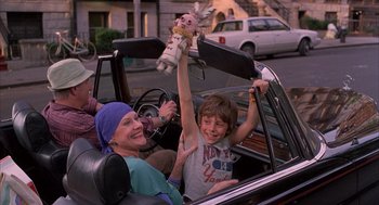 Movie still from “The Believers” (1987), directed by John Schlesinger – A woman and a boy in a car with a stuffed animal; Medium shot, Low angle