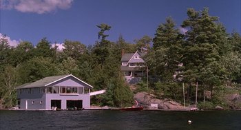 Movie still from “The Believers” (1987), directed by John Schlesinger – A house sitting on top of a hill next to a body of water; Extreme Wide shot, High angle