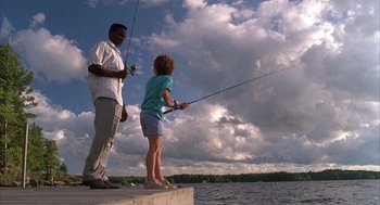 Movie still from “The Believers” (1987), directed by John Schlesinger – A man and a woman fishing on a pier; Wide shot, Low angle