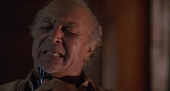 Movie still from “The Believers” (1987), directed by John Schlesinger – An older man is holding his head and looking at the camera; Close Up shot, Low angle