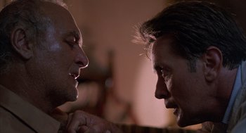 Movie still from “The Believers” (1987), directed by John Schlesinger – Two men face each other in a room; Close Up shot, Low angle