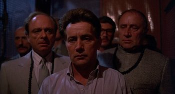 Movie still from “The Believers” (1987), directed by John Schlesinger – A group of men standing next to each other in a room; Close Up shot, Low angle