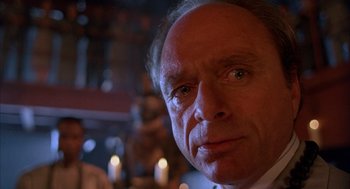 Movie still from “The Believers” (1987), directed by John Schlesinger – An older man looking at the camera in a restaurant; Extreme Close Up shot, Low angle