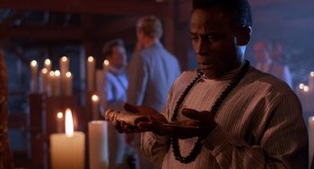 Movie still from “The Believers” (1987), directed by John Schlesinger – A man holding a candle in front of a candle holder; Close Up shot, Low angle